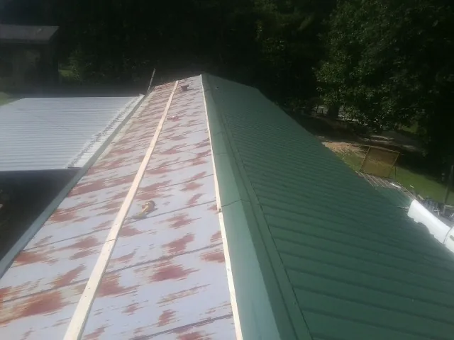 Old rusted panels beside newly installed green metal roofing — Wind Damage Roof Repair by Roofing Brothers in Lake Geneva