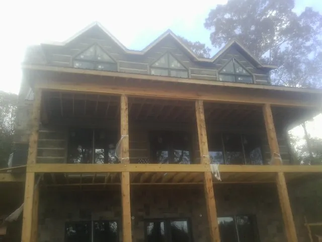 Dormers and porch framing on a large log home under construction — Roof Coating work by our crew in Lake Geneva
