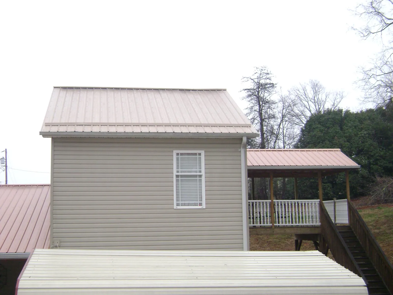 Tan metal roofs on a two story addition and attached porch, from a Roof Replacement job in Lake Geneva