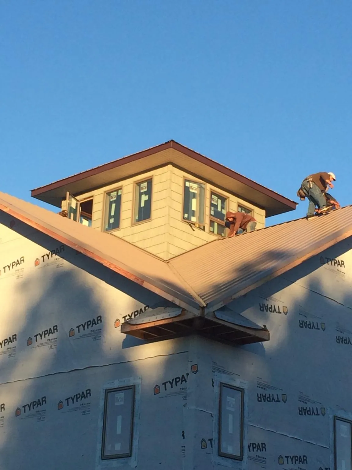 Roofers working around a rooftop cupola on a new metal roof at sunset — Roof Waterproofing in Lake Geneva by Roofing Brothers